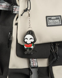 Small hooded skull charm hanging from a backpack with a metal ring and chain