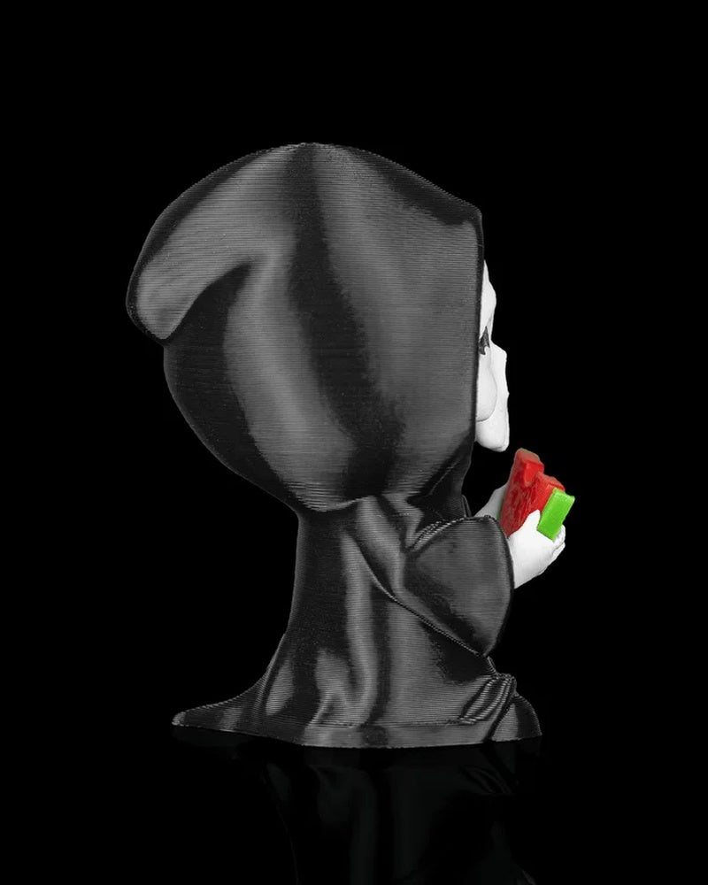 Side view of a black hooded figurine holding a watermelon slice on a black background