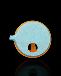 Bottom view of a blue circular toy base with an orange rim and small side protrusion on a black background