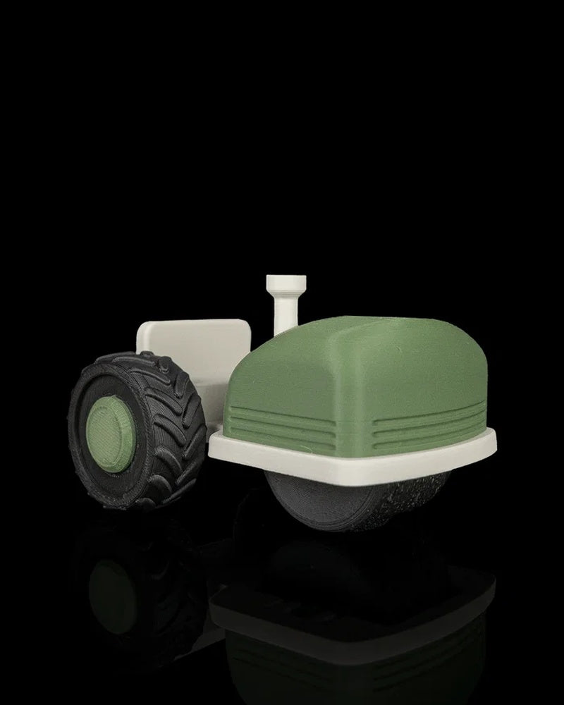 Green and off-white tractor-shaped roller tool with black treaded wheel on a black background.
