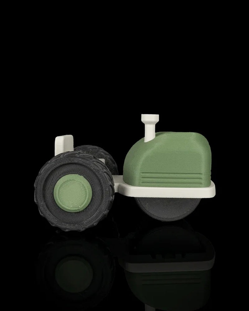 Side view of a green and off-white tractor-shaped roller tool with a black treaded wheel.