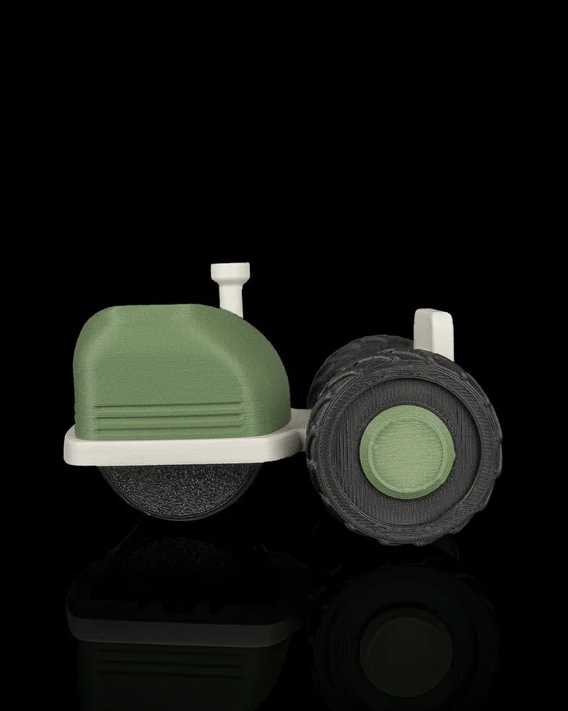 Side view of the tractor-shaped tool with a green body, off-white base, and black treaded wheel.