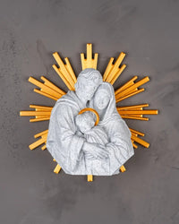 Top view of a white Holy Family figurine with gold-tone rays on a gray surface