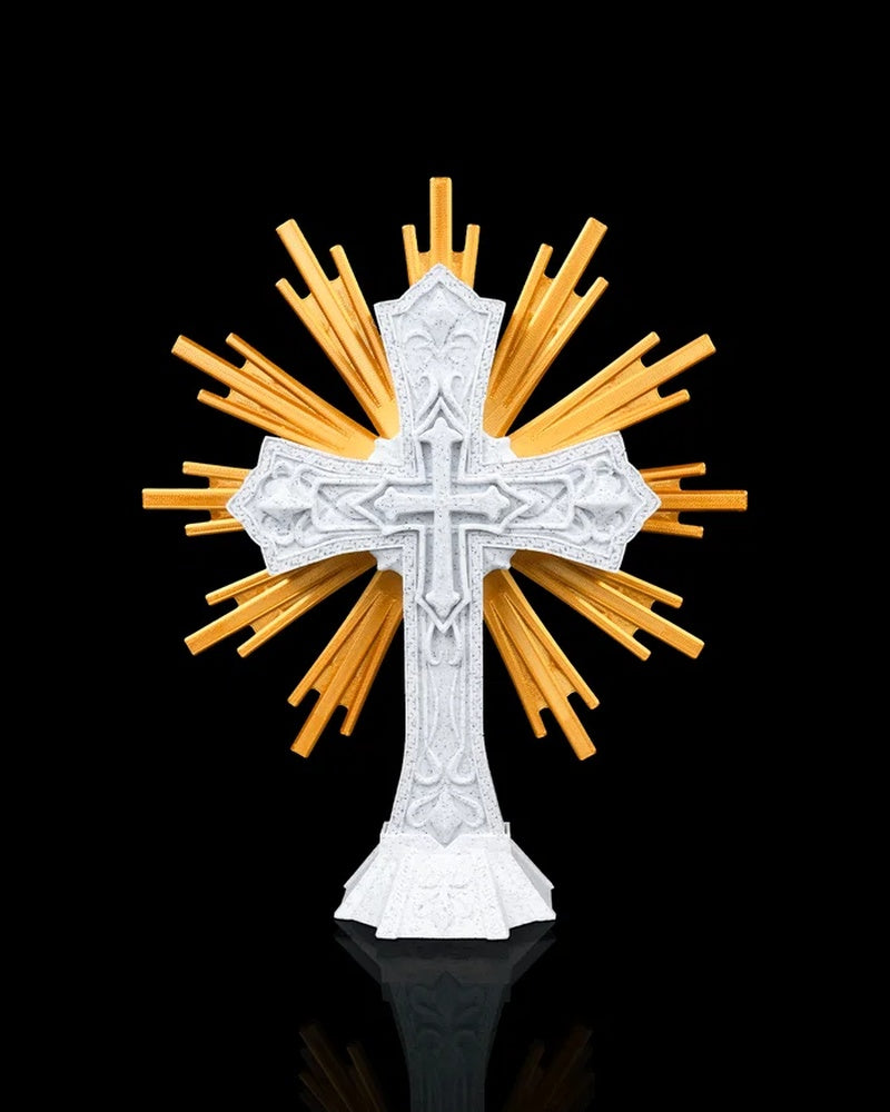 White ornate cross figurine with gold-toned rays on a black background