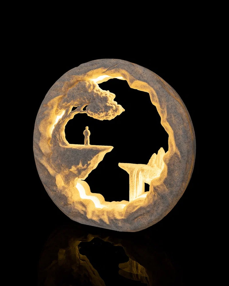 Angled front view of a glowing circular rocky scene with a small figure standing on a cliff