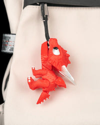 Red dragon toy hanging from a black loop on a light fabric bag