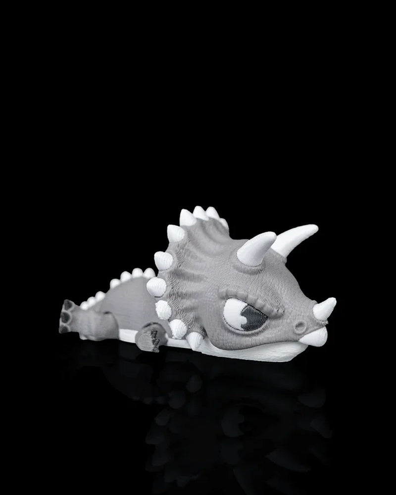 Gray and white triceratops dinosaur toy on a black reflective surface