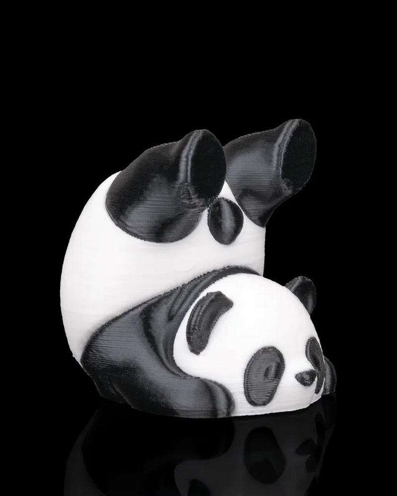 Side view of a black and white panda figurine with rounded body and panda face detail