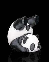 Side view of a black and white panda figurine with rounded body and panda face detail