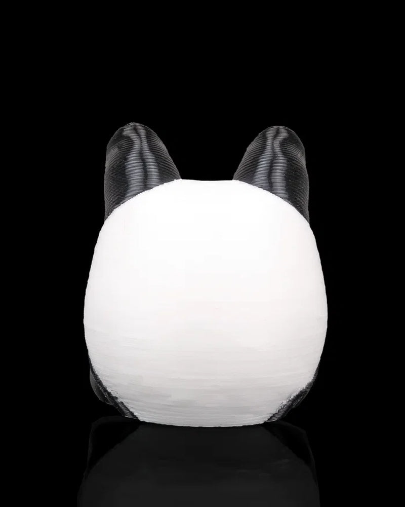 Back view of a rounded black and white panda figurine with two black ears