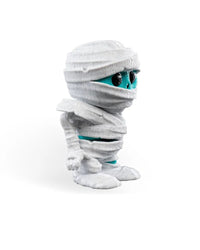 Side view of a white wrapped monster figurine with turquoise face details and rounded feet on a plain background.