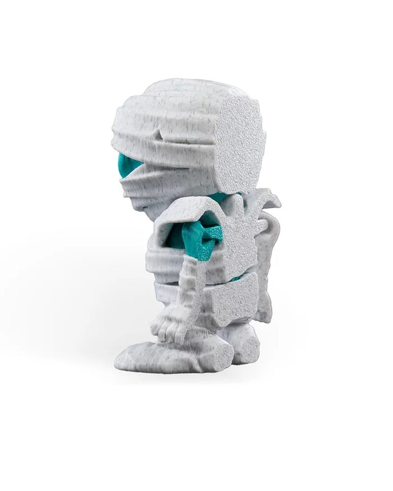 Left side view of a white wrapped monster figurine showing turquoise body areas and layered back details.