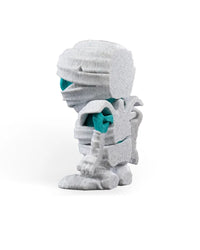 Left side view of a white wrapped monster figurine showing turquoise body areas and layered back details.