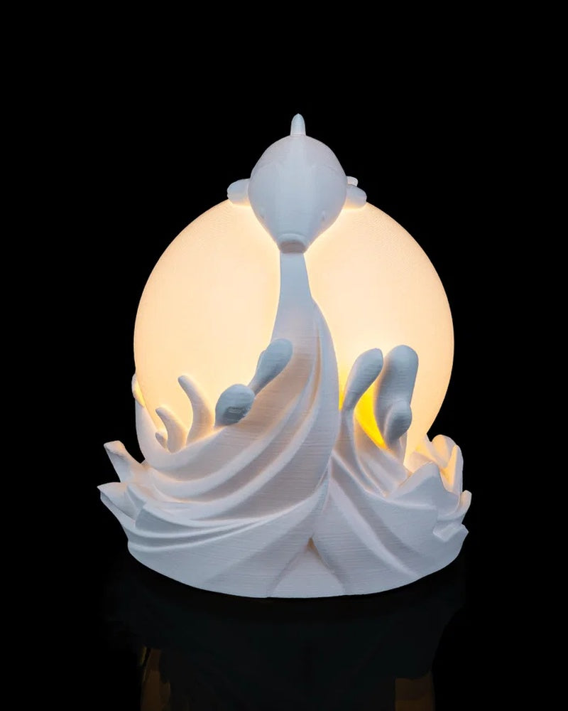 Rear view of a white fish and wave lamp with a glowing round center on a black background.