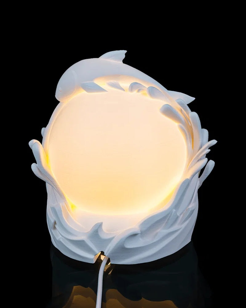 White fish and wave forms frame a glowing round center with a cord visible below.