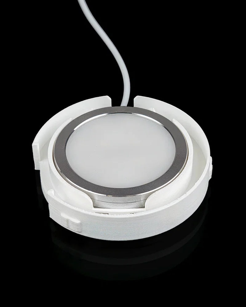 Underside view of a circular white base with a round light panel and cord.