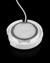 Underside view of a circular white base with a round light panel and cord.