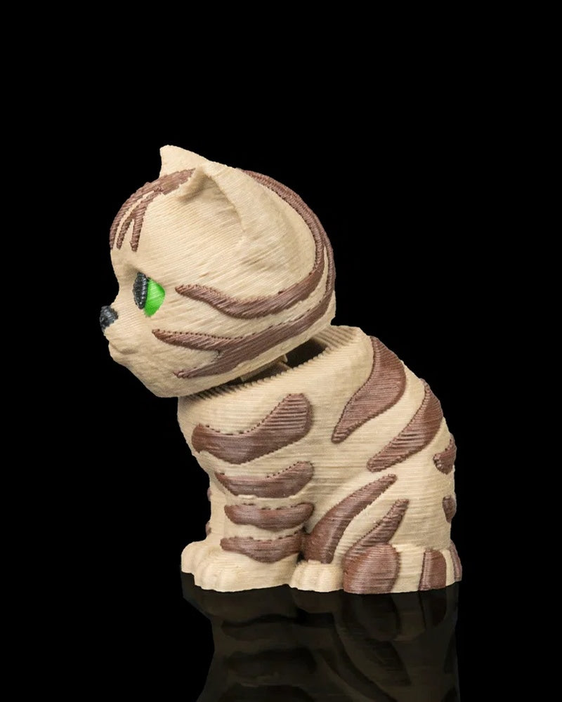 Cream and brown striped tabby cat figurine with green eyes on a black background
