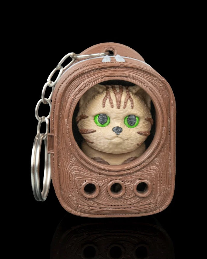 Brown backpack-shaped carrier with a tabby cat face inside and a metal ring on the side