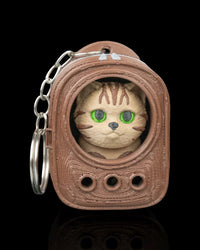 Brown backpack-shaped carrier with a tabby cat face inside and a metal ring on the side