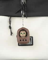 Brown backpack-shaped cat figure hanging from a bag zipper by a metal ring and chain