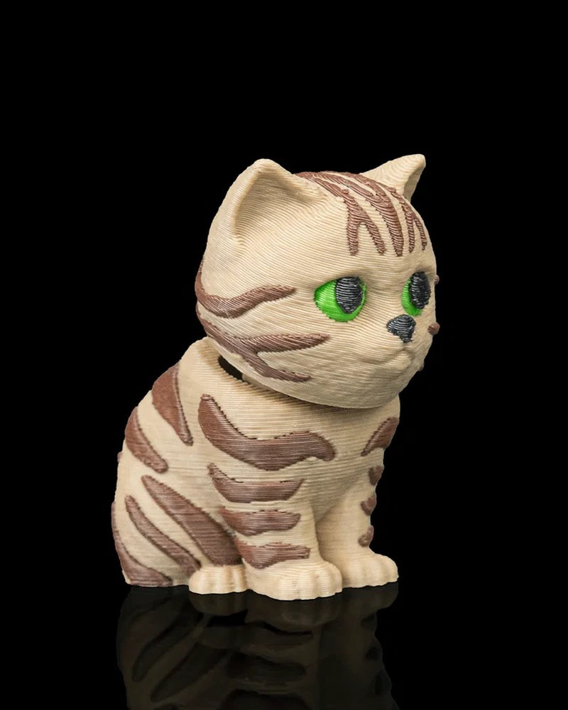 Angled side view of a cream and brown tabby cat figurine with green eyes