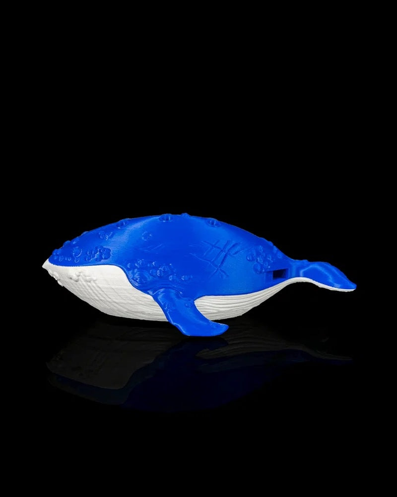 Blue and white whale figurine on a black reflective surface viewed from the opposite side