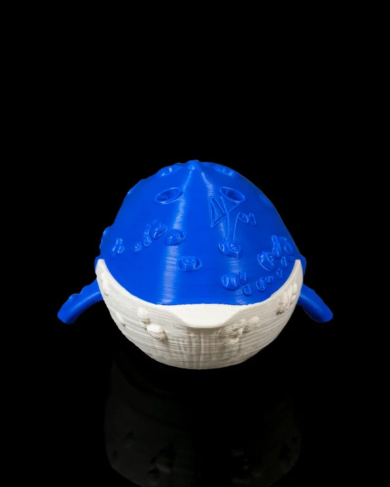 Front view of a blue and white whale figurine with raised surface details