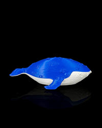 Side view of a blue and white whale figurine with flipper and tail visible