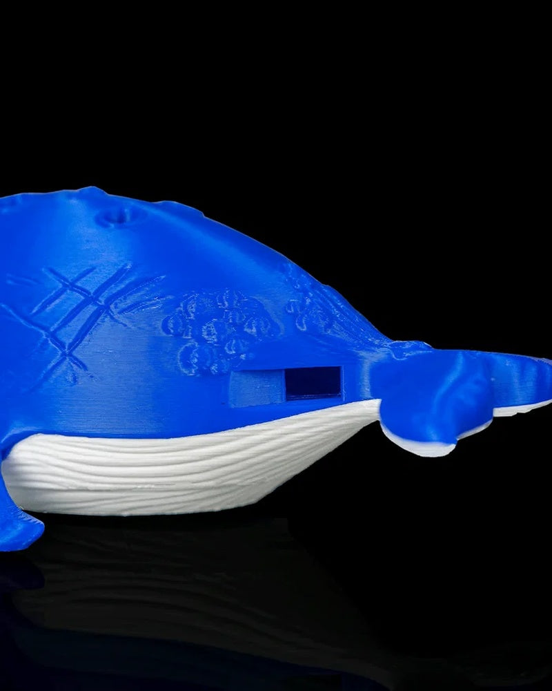 Close-up of the side of a blue and white whale figurine with a rectangular opening