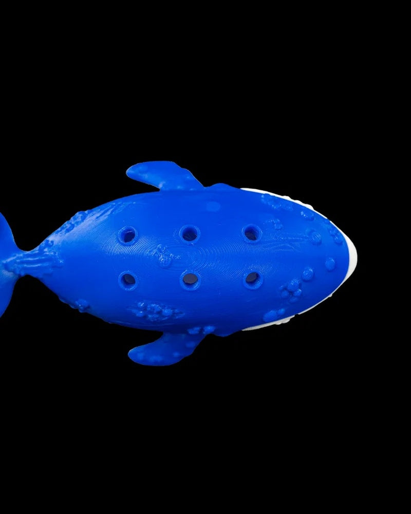 Top view of a blue whale figurine with circular holes and raised details