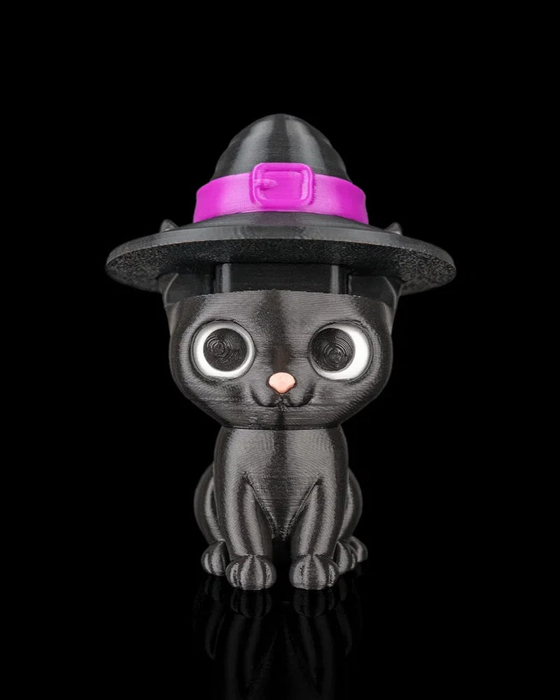 Front view of a black cat figurine wearing a wide-brimmed witch hat with a bright pink band on a black background.