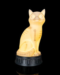 Glowing cat-shaped lamp on a dark round base against a black background