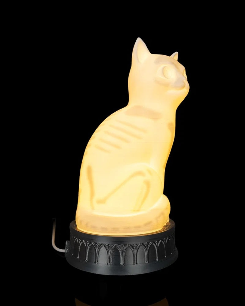 Side view of a glowing cat-shaped lamp with a white cord visible behind the base