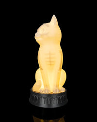 Front side view of a glowing cat-shaped lamp on a dark round base