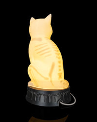 Back view of a glowing cat-shaped lamp with skeletal-style markings and a cord near the base